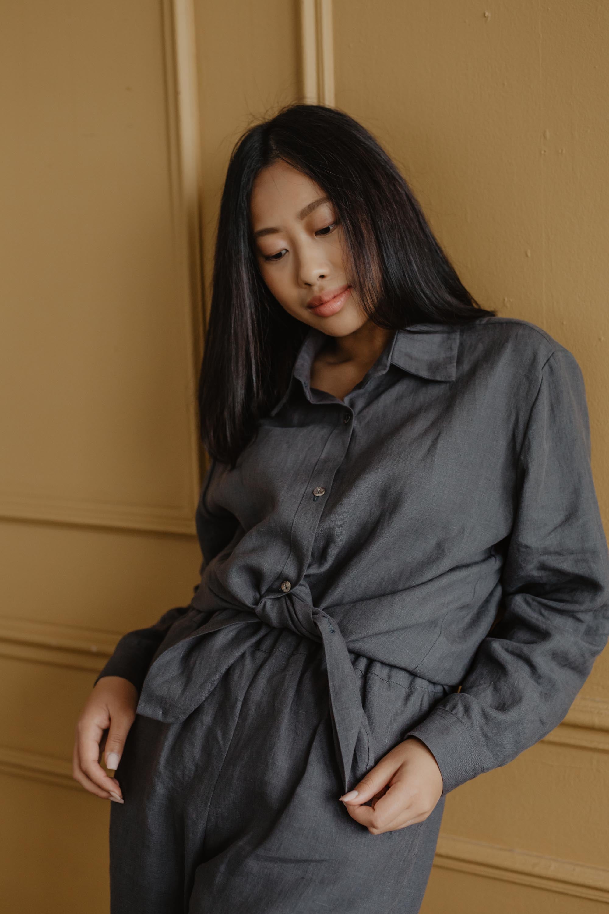 Woman Leaning On Wall Wearing A Charcoal Linen Casual Shirt And Linen Pants