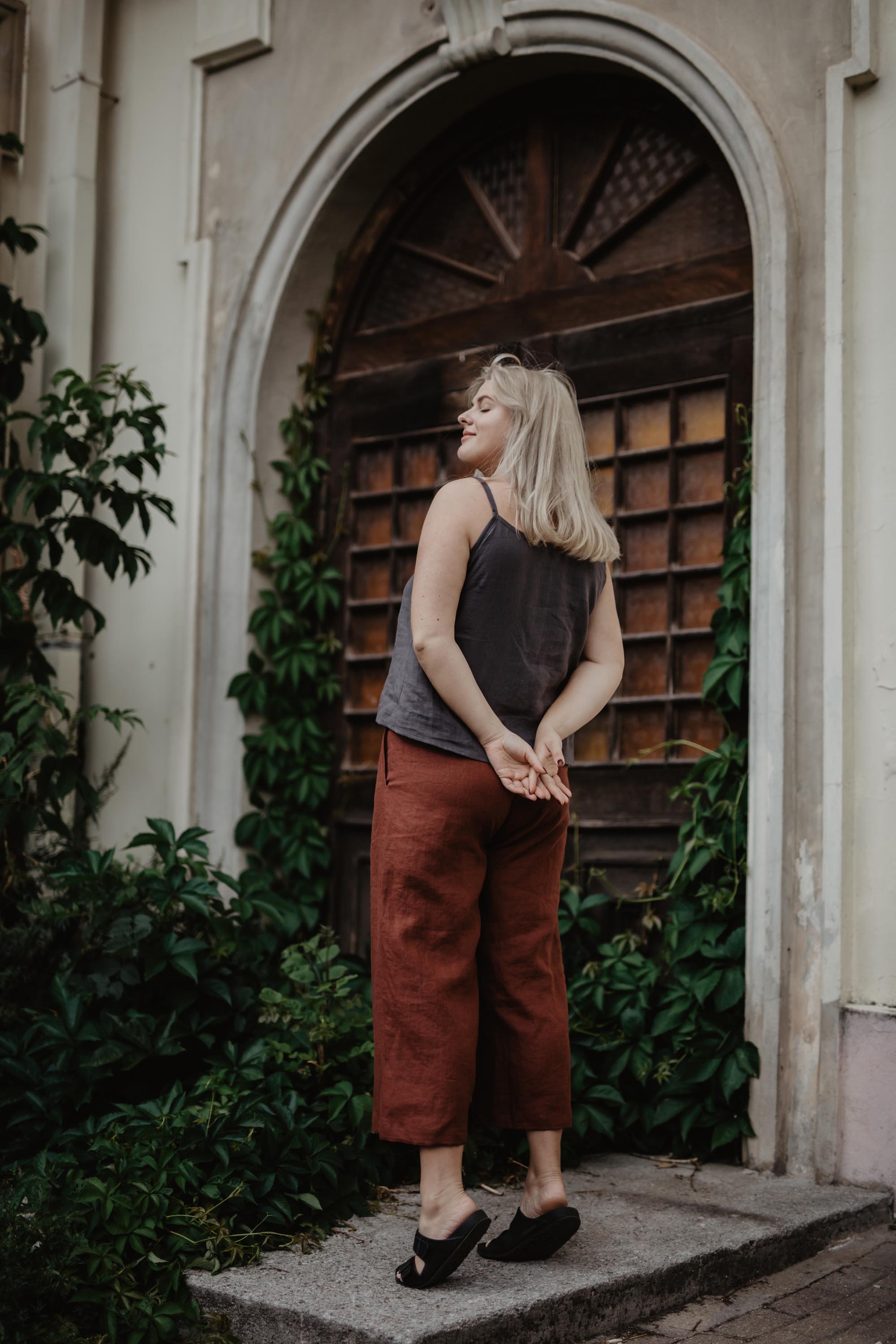 Woman Facing Back Wearing Terracotta Linen Pants and Dark Linen Top