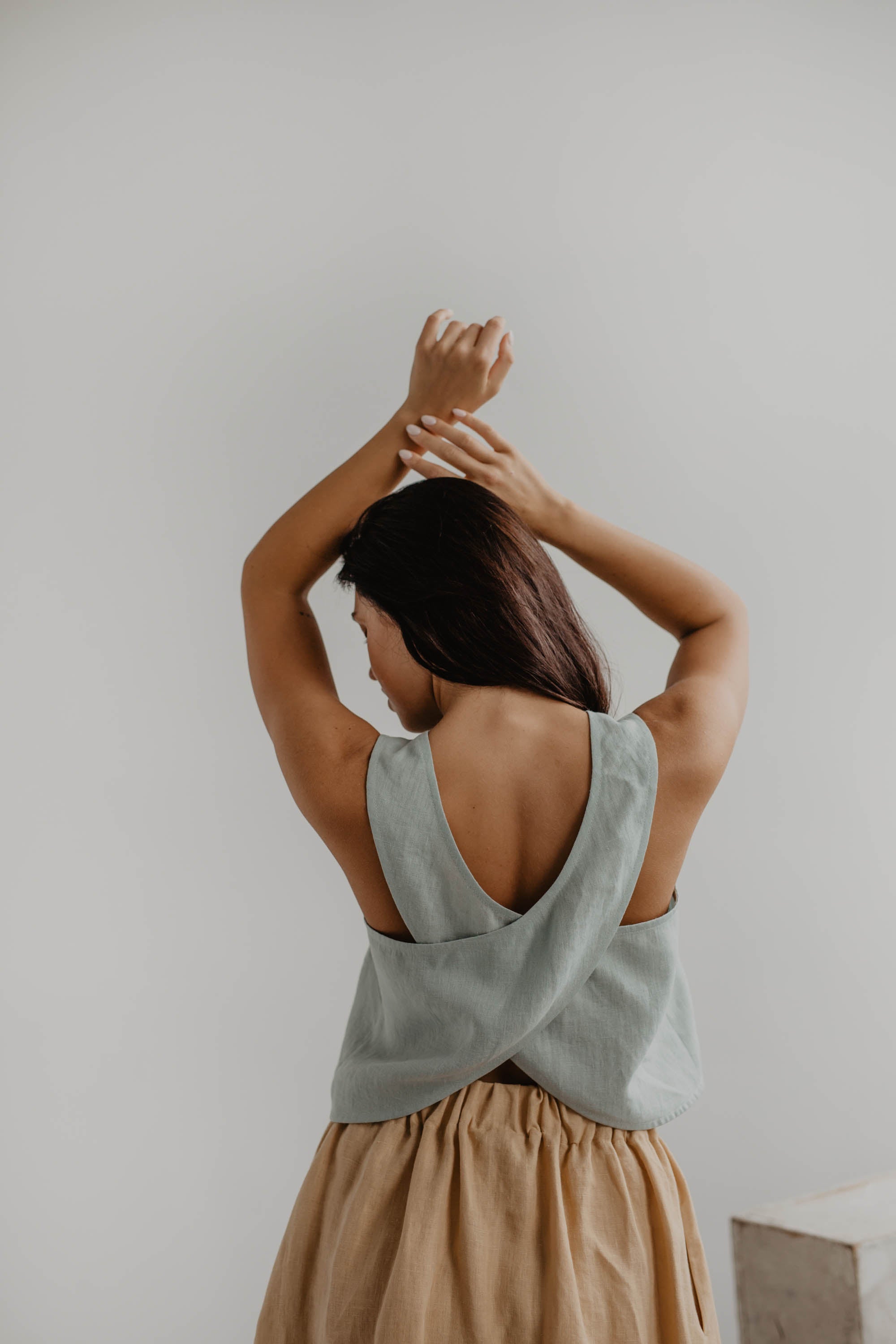 Close up Of Back Of A Woman Wearing A Sage Green Linen Pinafore Top