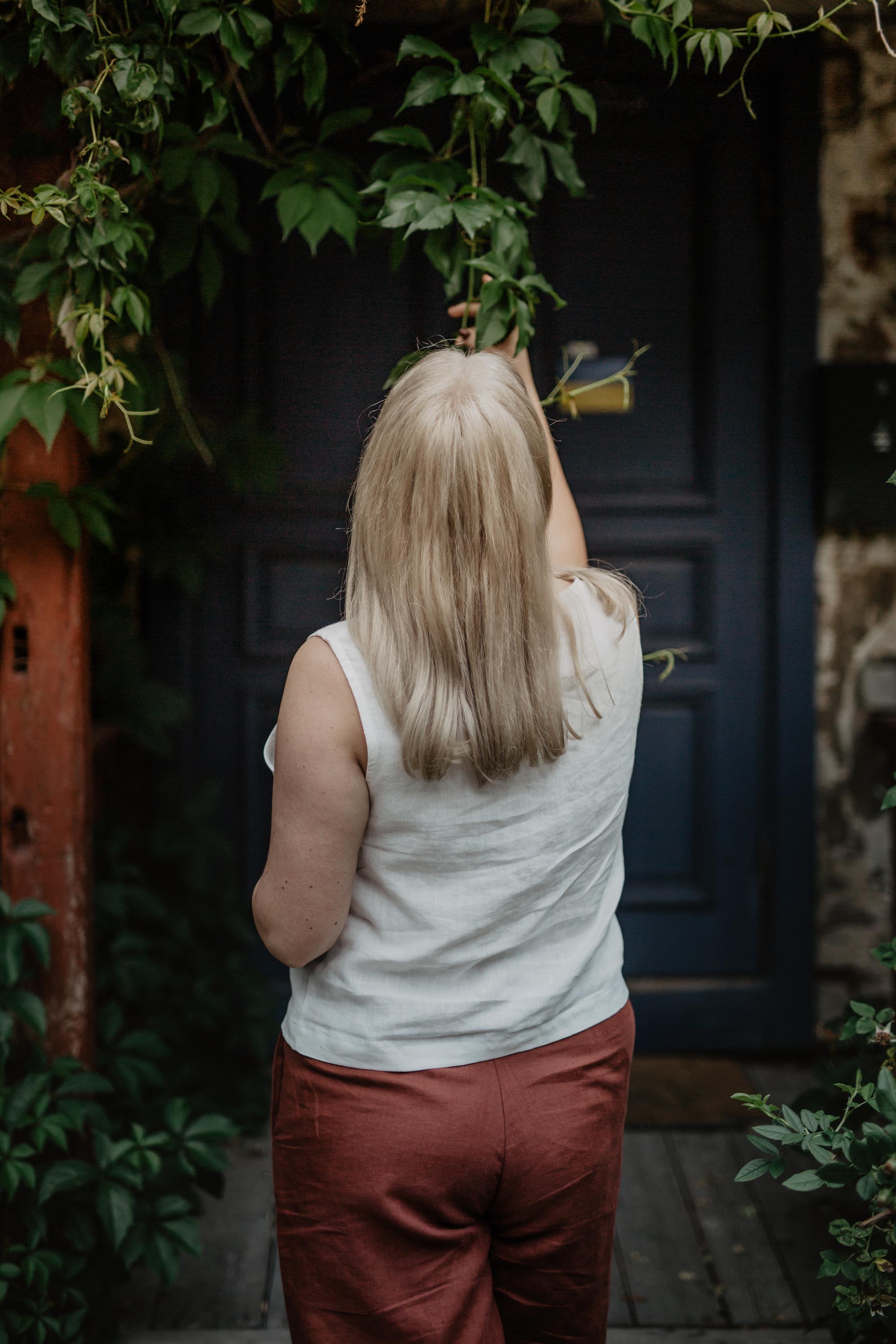 Woman Facing Back Wearing A White Linen Button Top and Terracotta Linen Pants By Amourlinen