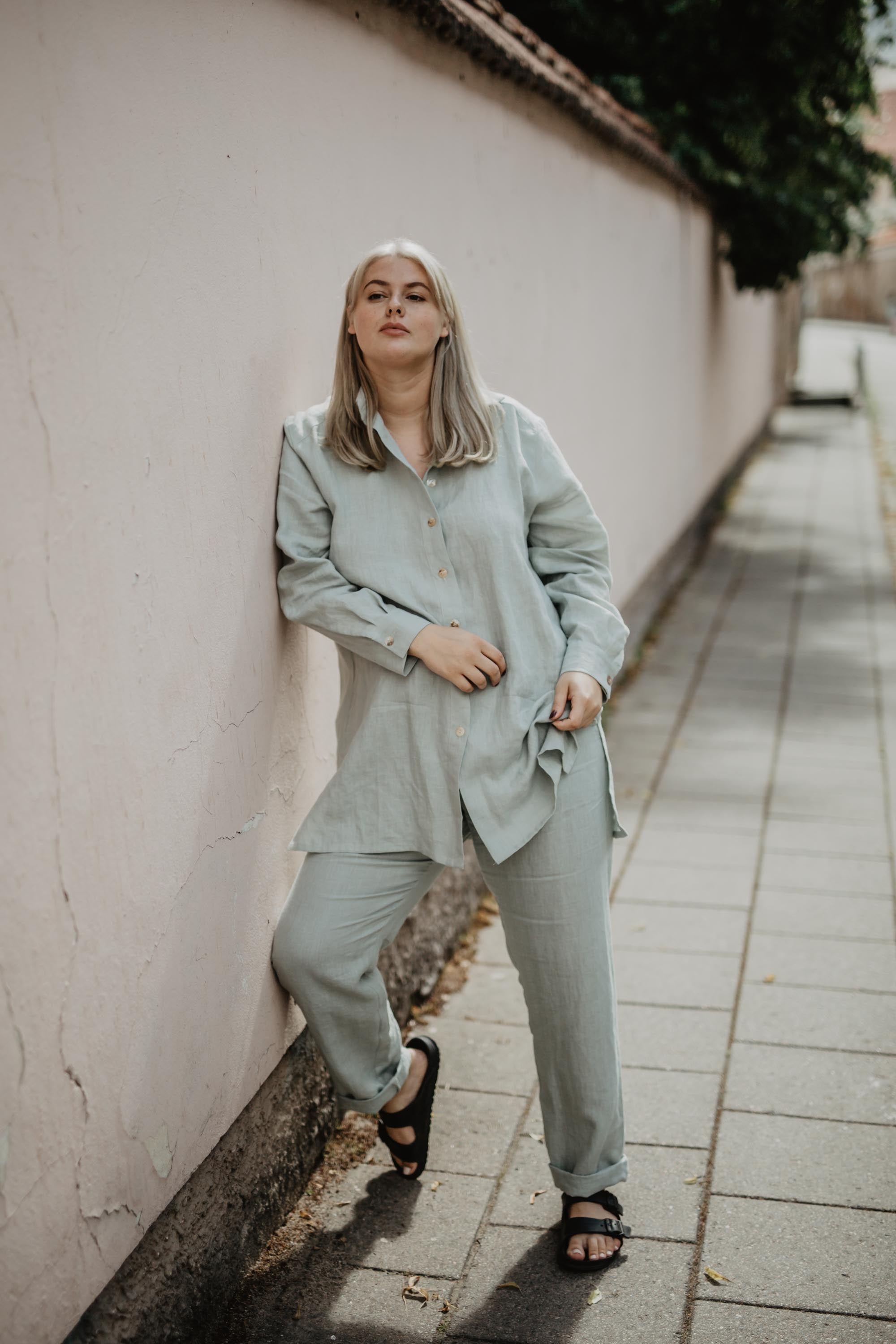 Woman Leaning On Wall Wearing Sage Green Linen Suit Set By AmourLInen