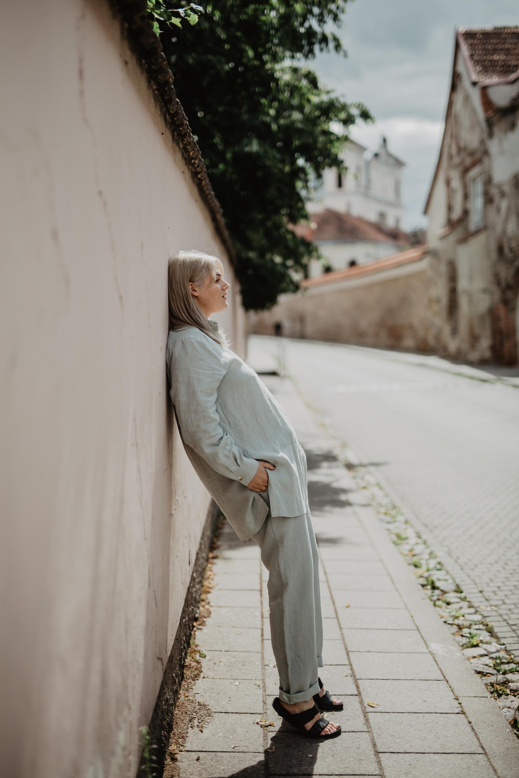Woman Leaning On Wall Wearing Sage Green Linen Suit Set