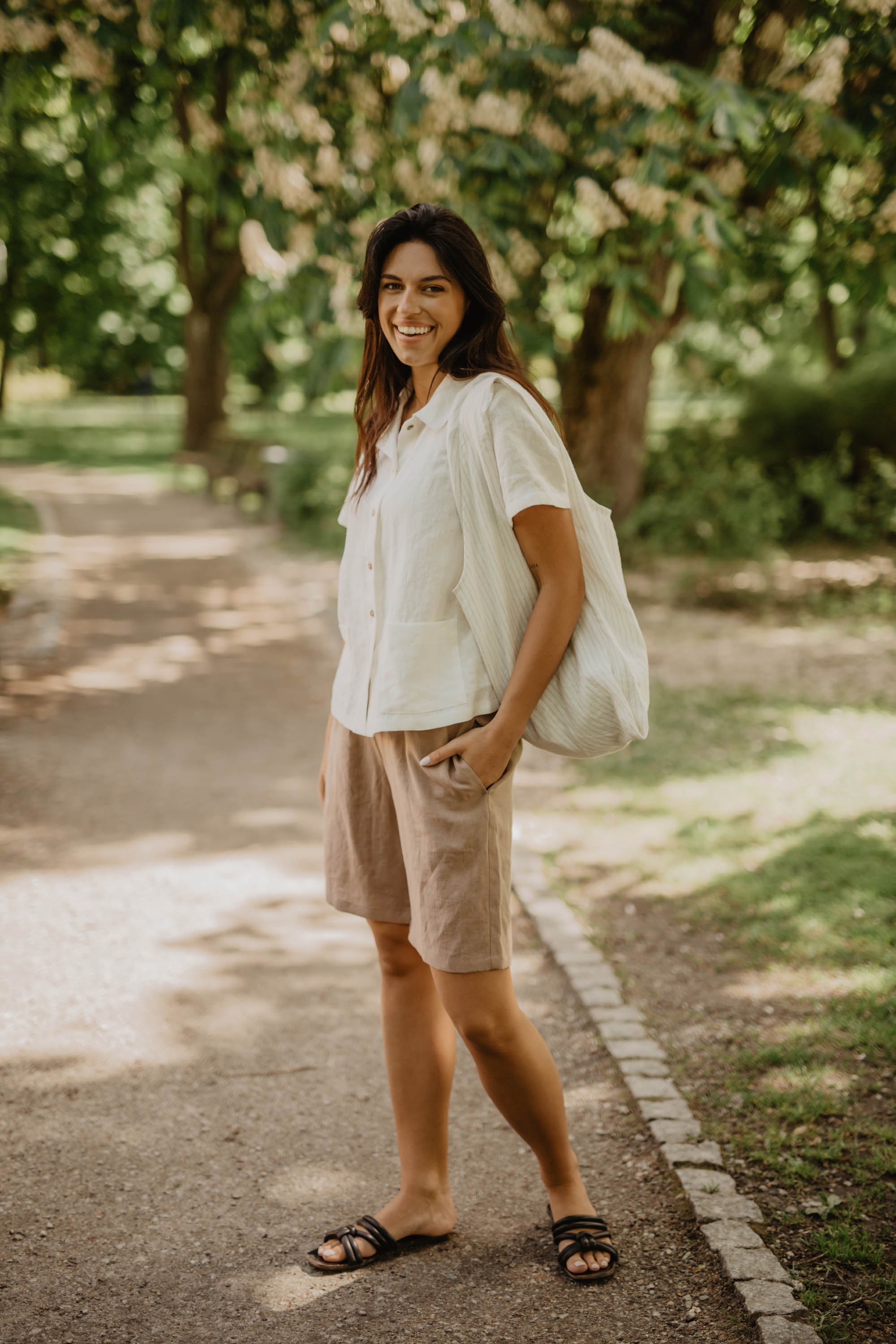 Woman In Park Posing In Cream Color Long Linen Shorts